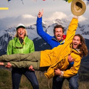 Three explorers waving from in front of a mountain